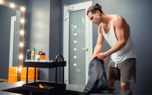 Sportler in Muscle Shirt packt seine Trainings tasche in Umkleide