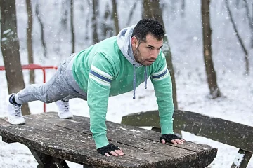 Fitness Outdoor training im Winter Mann draußen macht Liegestütze im Winter